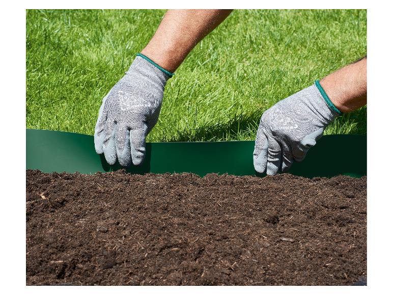 Mains gantées de jardinage installant une bordure de pelouse verte entre l'herbe et la terre.