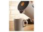 Bouilloire claire versant de l'eau dans une tasse sur un comptoir en bois.