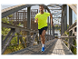 Un homme court sur un pont, vêtu d'un t-shirt jaune et de chaussures de course bleues.