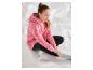 Fille en sweat à capuche rose imprimé léopard et leggings noirs assise sur du papier blanc.