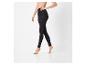 Une femme présente un legging noir taille haute sur fond blanc.