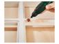 Roterend gereedschap met schuurhulpstuk op wit geschilderd hout.