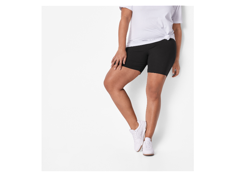 Plus size model draagt zwarte fietsbroek en witte sneakers.