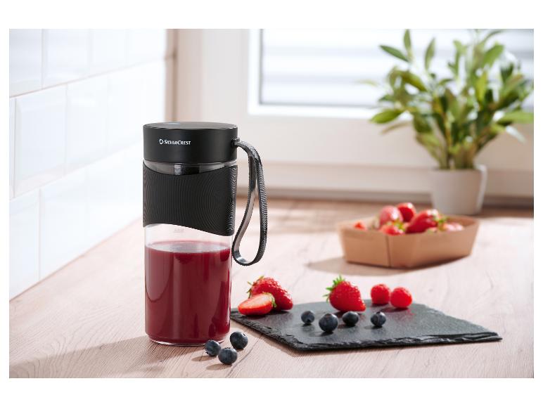 Mixeur portable SilverCrest avec smoothie rouge et fruits frais sur une planche en bois.