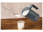 Een grijze SilverCrest melkopschuimer giet opgeschuimde melk in een glas.