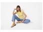 Femme en t-shirt jaune, jean bleu et chaussures plates jaunes, assise sur le sol.