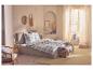Gezellige slaapkamer met tweepersoonsbed, geruit beddengoed, rotan fauteuil en natuurlijke decoraties.