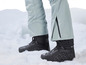 Zwarte sneeuwschoenen met grijze ski broek in de sneeuw.