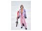 Fille heureuse en veste de ski florale colorée et pantalon de ski rose avec skis et bâtons.