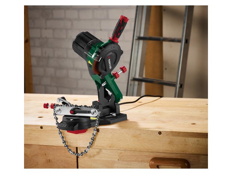 Affûteur de chaîne électrique sur un établi en bois dans un atelier.