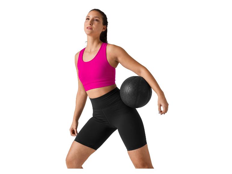 Vrouw in sportkleding met een medicijnbal.