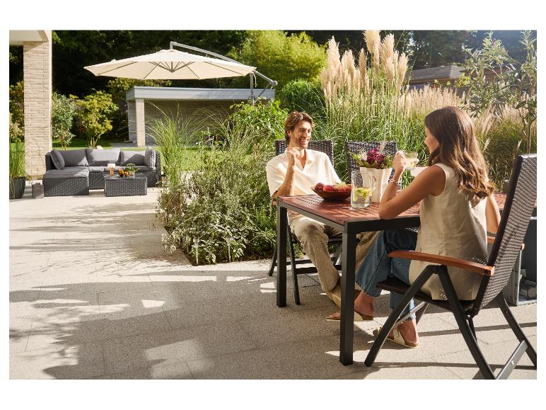 Paar geniet van buitenmaaltijd op terras met tuinmeubelen en parasol.