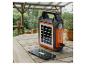 Chargeur solaire portable noir et orange avec un téléphone en charge sur une table en bois.