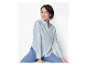Vrouw zittend in een lichtblauw shirt en jeans.