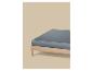 Een bed met een licht houten frame en een donkergrijs hoeslaken.