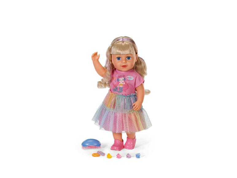 BABY born pop met blond haar, roze top, regenboogrok en accessoires.