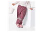 Meisje in roze regenbroek en roze laarzen houdt een witte emmer vast.