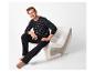 Homme en pyjama rayé noir et pantalon de pyjama noir assis sur une chaise blanche.