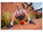 Jongen in grijs T-shirt en spijkerbroek zittend op een basketbal.