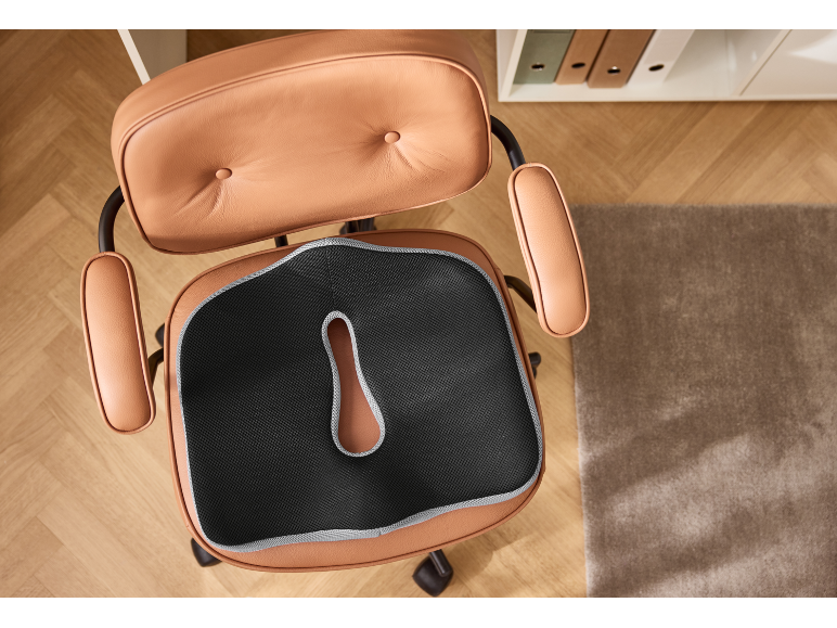 Coussin ergonomique sur une chaise de bureau en cuir marron, vue de dessus.