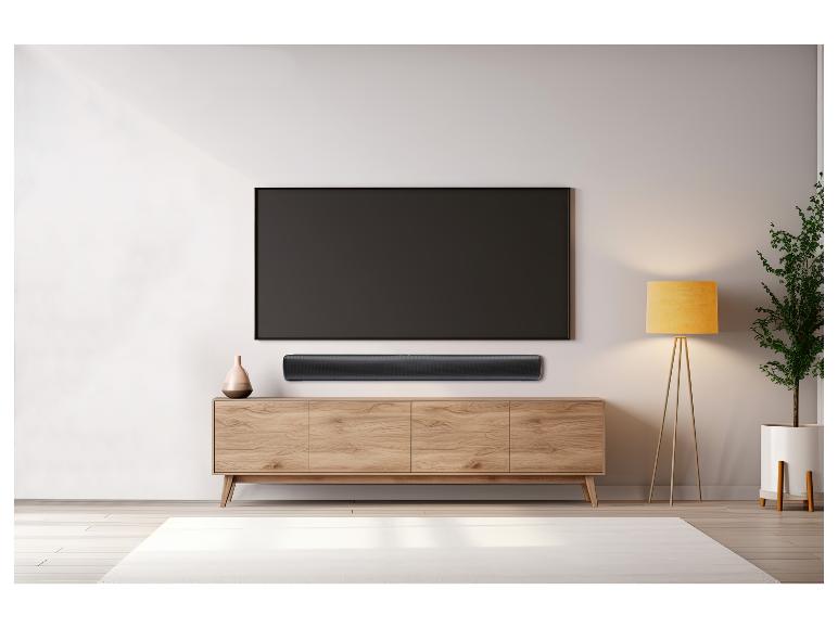 Een zwarte soundbar onder een tv op een houten tv-meubel.