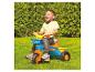 Een kind rijdt op een Hot Wheels driewieler in de tuin.