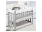 Lit bébé gris avec literie blanche et coussins décoratifs.