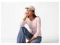 Vrouw met beige pet, roze shirt met lange mouwen en jeans, gehurkt.