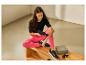 Femme assise sur un banc en bois utilisant un masseur sur son bras, avec étui et accessoires.