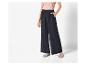 Pantalon large noir et sandales plates : look élégant et décontracté.
