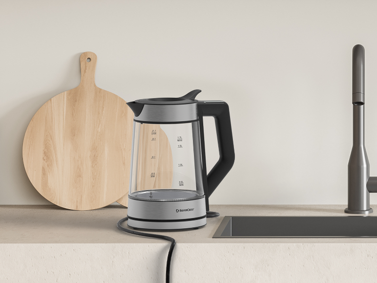 Glazen waterkoker en houten snijplank op een modern aanrecht.
