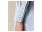 Detail van een lichtblauwe blouse met knopen.