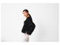 Femme en pull en maille noir et pantalon blanc, regardant par-dessus son épaule