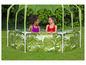 Twee meisjes in een opblaasbaar zwembad met een palmblad motief en een groene parasol.