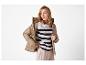 Femme porte une doudoune beige, un pull rayé noir et blanc et un pantalon beige.