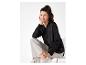 Een vrouw draagt een zwarte blouse met lange mouwen en beige broek.