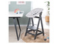 Une chaise haute Stokke Tripp Trapp grise avec un set Stokke Newborn gris dans une chambre d'enfant.