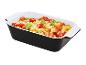 Pâtes gratinées aux tomates cerises, fromage et basilic dans un plat noir et blanc.