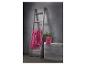 Serviettes roses suspendues à une échelle en bois et pliées sur un banc gris avec une plante.