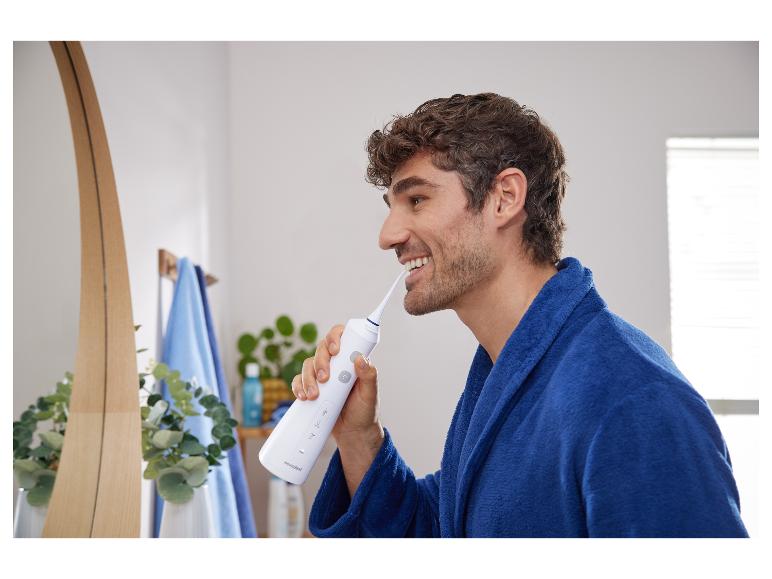 Man gebruikt een waterflosser van Nevadent in de badkamer.