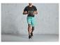 Homme en t-shirt noir et short bleu tenant un ballon de médecine.