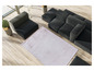 Een roze vloerkleed op een houten vloer met een zwarte modulaire bank.