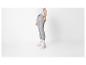 Femme en legging gris, t-shirt blanc et baskets blanches.
