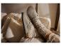 Pieds en chaussons gris et chaussettes tricotées sur un canapé douillet.