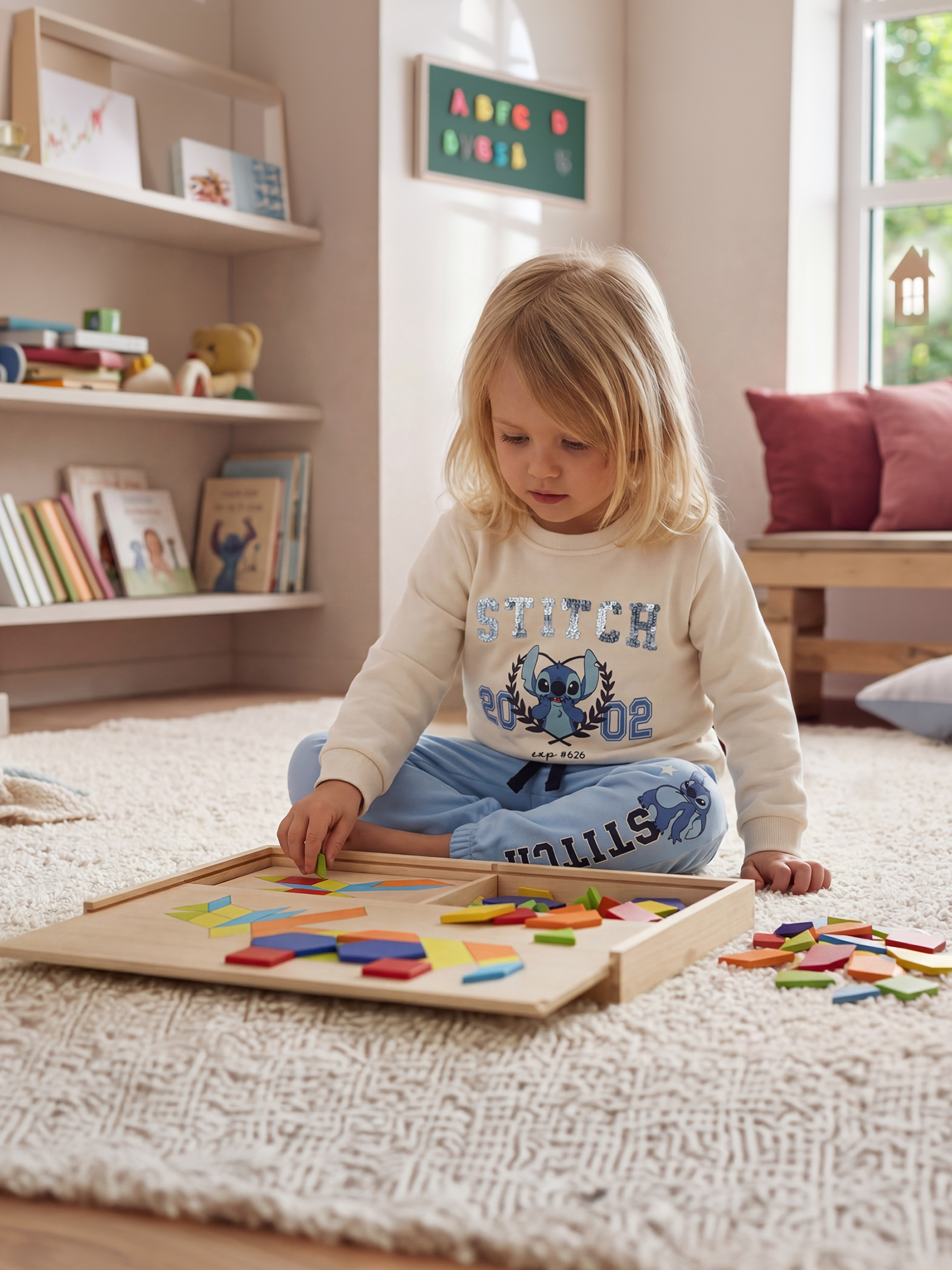 Enfant jouant avec un puzzle en bois coloré sur un tapis moelleux, portant un pull et un pantalon de survêtement.