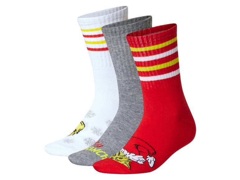 Drie paar Grinch-thema sokken: wit, grijs en rood, met strepen en patronen.