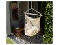 Chaise suspendue en tissu avec coussins sur un patio avec carrelage et plantes.