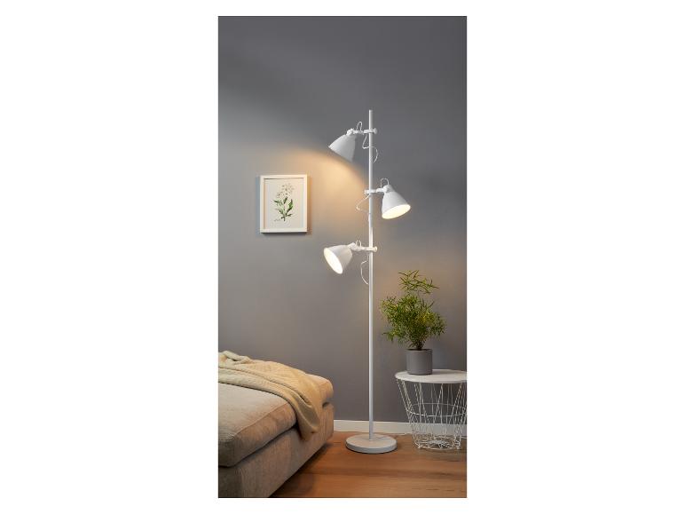 Un lampadaire blanc avec trois lampes dans un salon.