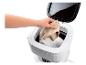 Main plaçant des chaussettes dans une machine à laver portable compacte avec un couvercle ouvert.