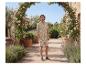 Man in beige overhemd en korte broek met bladprint, in een tuin.